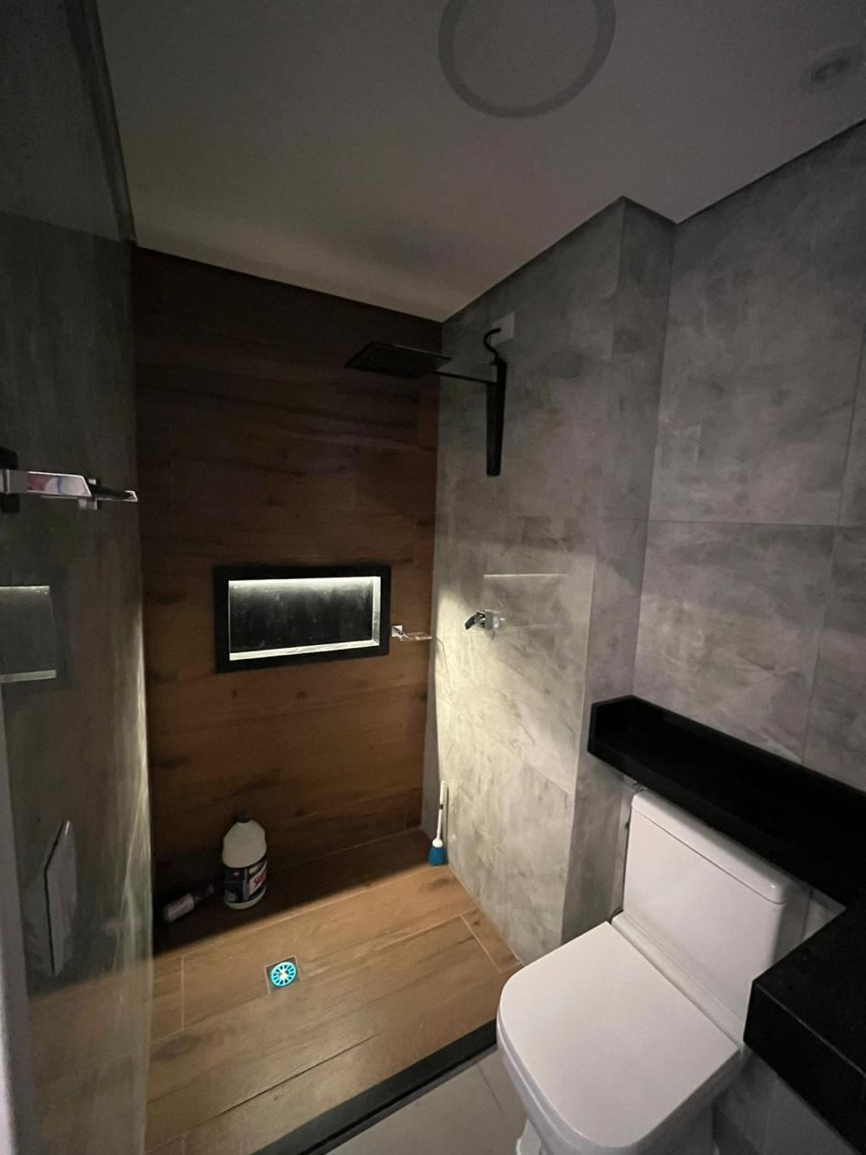 Banheiro pronto com box revestido em madeira e nicho iluminado