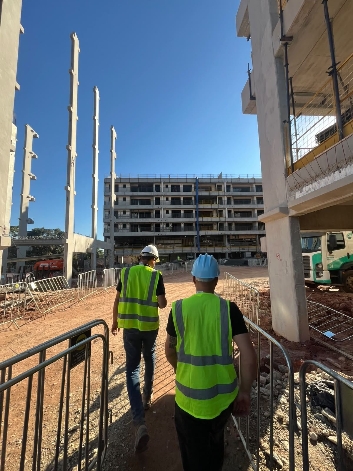 Equipe da Cavalcante Construções em canteiro de obra, com capacete e colete de segurança